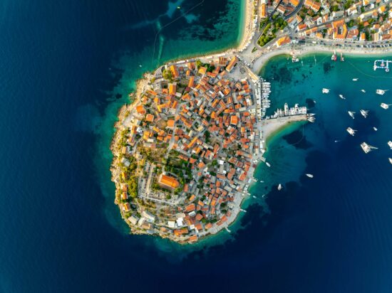 Aerial view of Primosten old town set on a tiny island connected to the mainland by a narrow causeway.